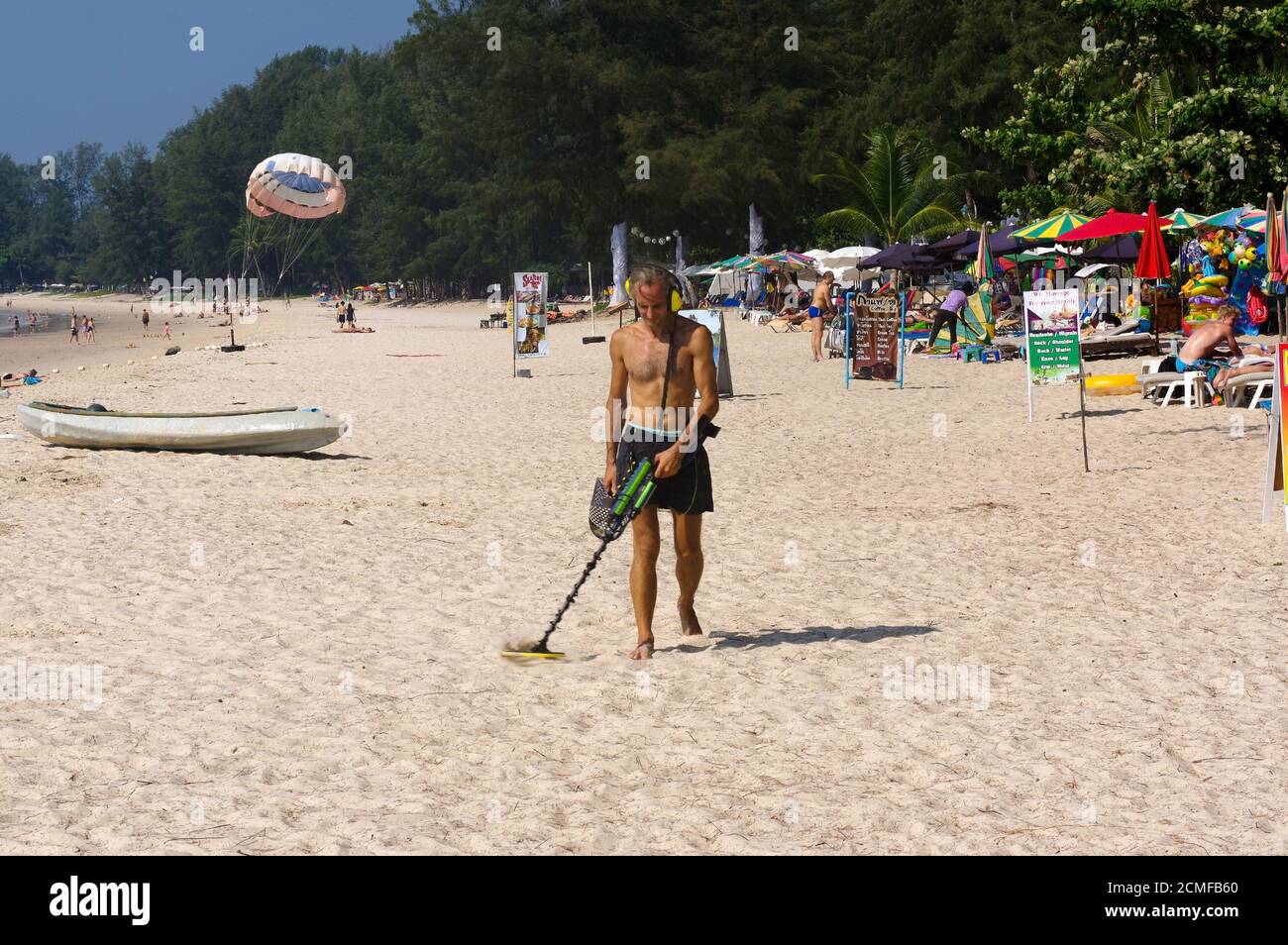 PHUKET, THAILAND - 25. MÄRZ 2016: Schatzsucher mit Metalldetektor am Strand Stockfoto