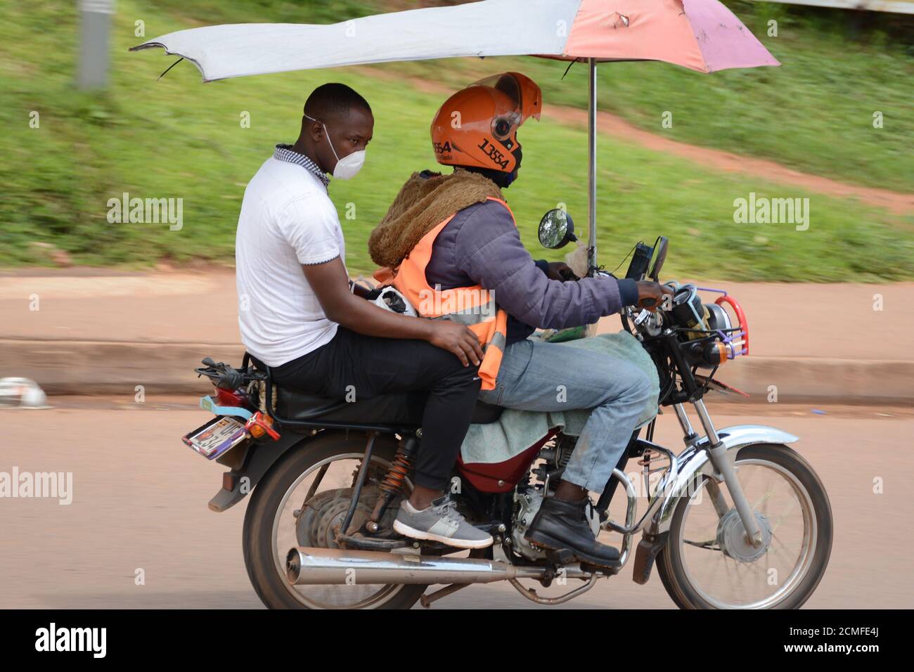 Kampala, Uganda. September 2020. Ein gewerblicher Motorradfahrer trägt einen Passagier in Kampala, der Hauptstadt Ugandas, 16. September 2020. Kommerzielle Motorradfahrer in Uganda haben den Online-Buchungsservice verstärkt, um ihre Kunden inmitten der COVID-19-Pandemie weiterhin zu bedienen. Quelle: Nicholas Kajoba/Xinhua/Alamy Live News Stockfoto