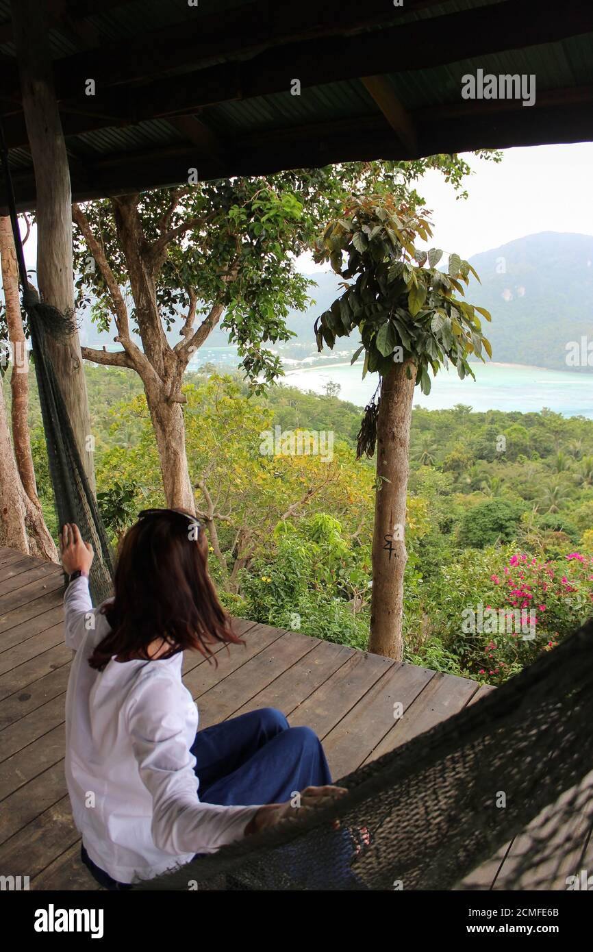 Lässige glückliche Frau, die sich in einer Hängematte mit Meerblick vom Aussichtspunkt, Krabbi Island, Thailand, entspannt Stockfoto