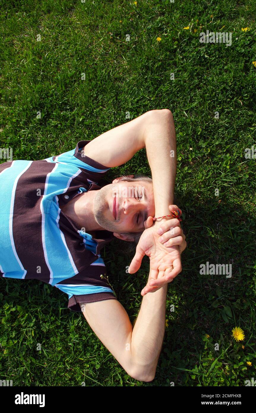 Porträt eines jungen glücklich entspannend auf dem Rasen mit seinen Händen unter dem Kopf Stockfoto