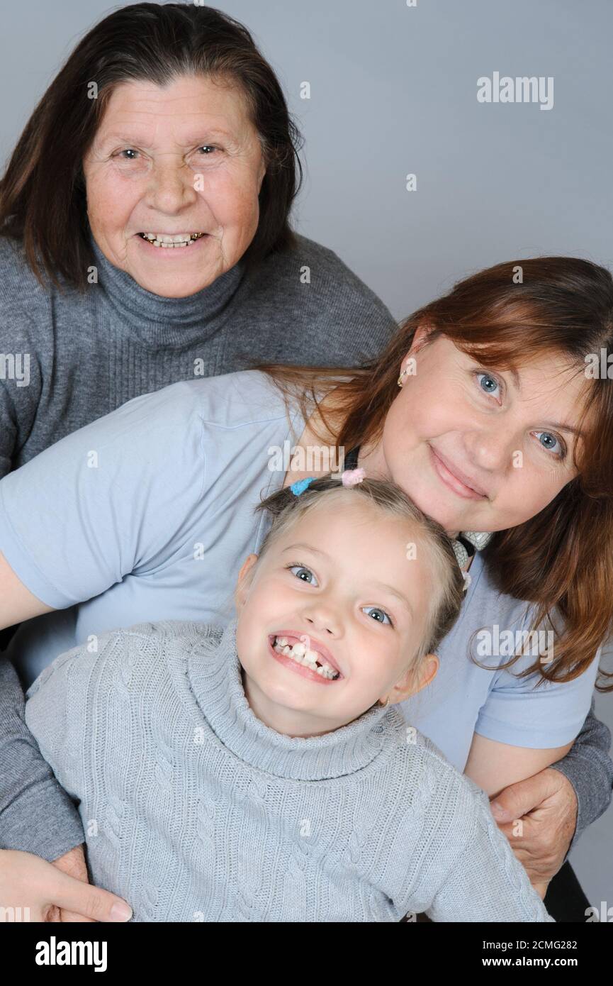 Kind mit ihrer Mutter und Großmutter umarmen einander auf dem Boden sitzen. Stockfoto