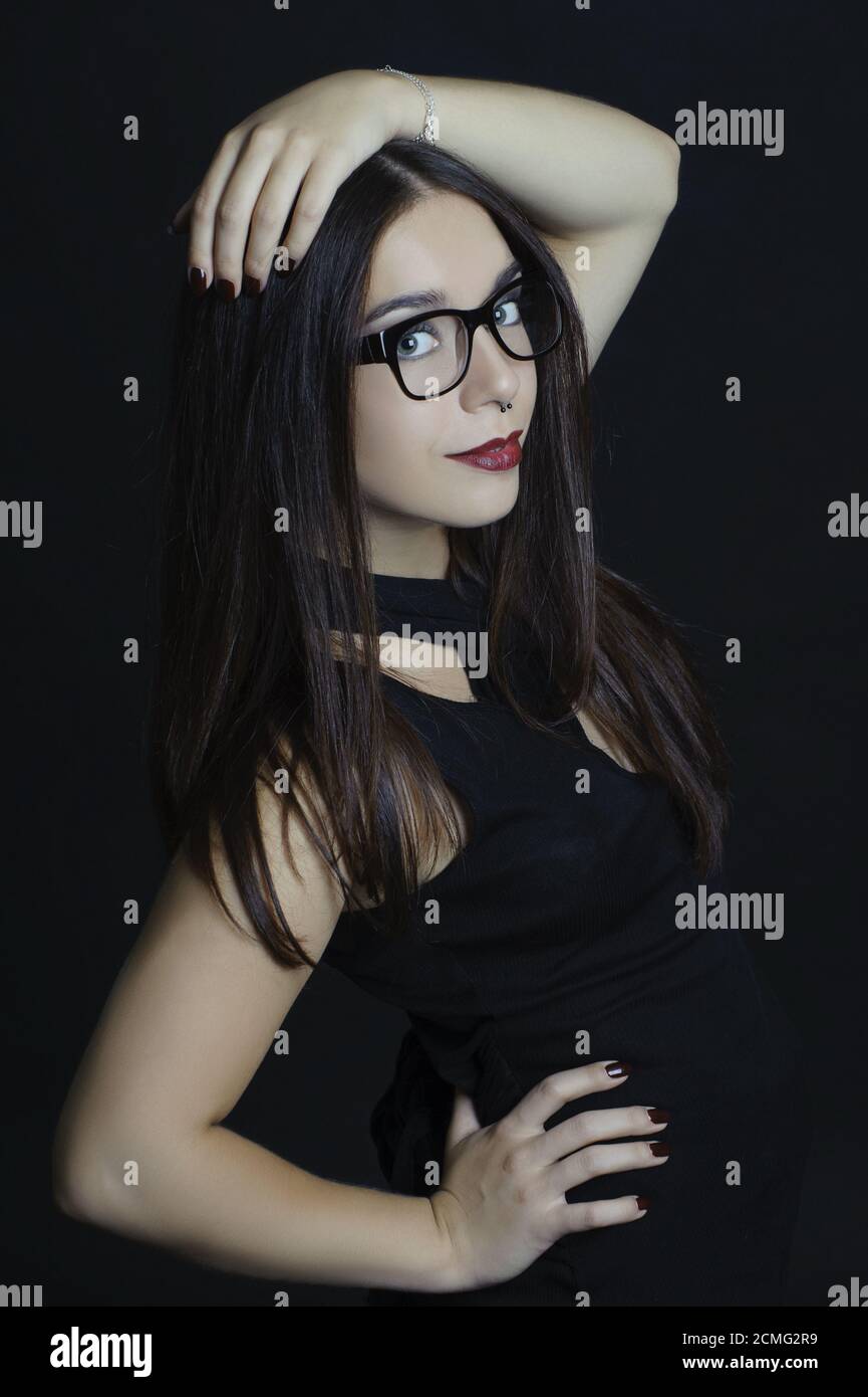 Stilvolle Mädchen mit großen Gläsern auf einem schwarzen Hintergrund. Stockfoto