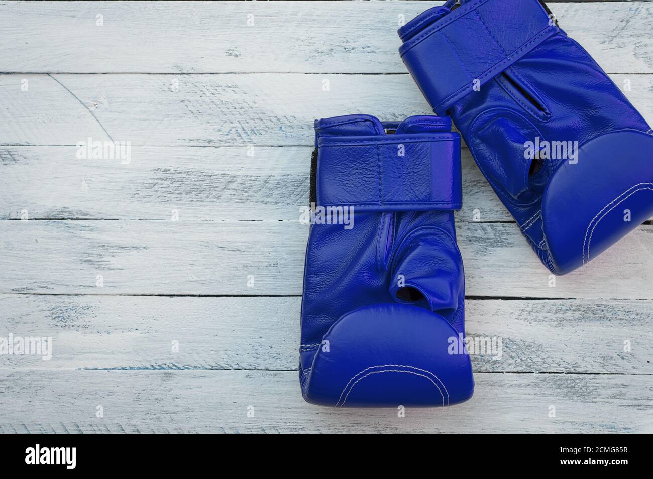 Ein Paar blaue Boxhandschuhe auf einer weißen Holzoberfläche Stockfoto