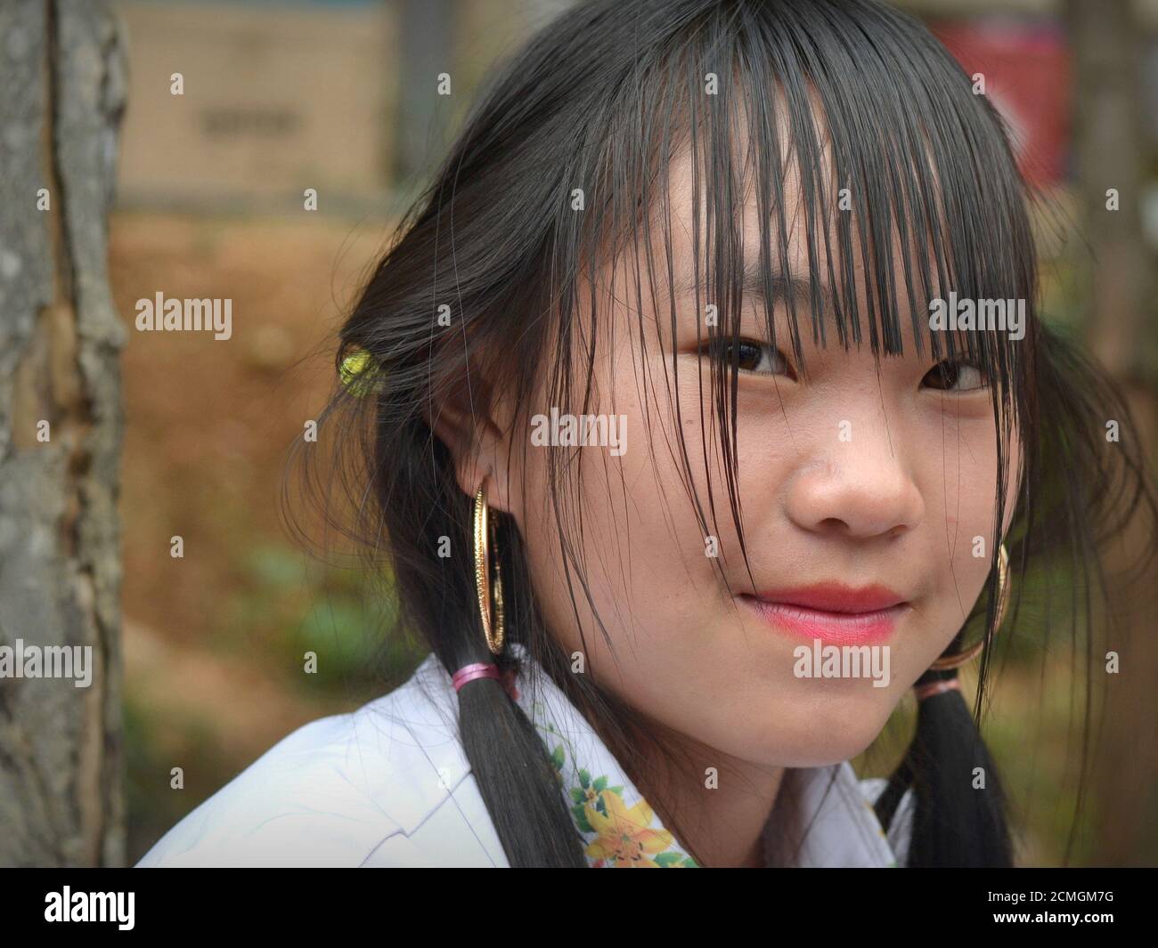 Moderne vietnamesische Hmong ethnische Minderheit Teenager-Mädchen mit langen Pony und Gold Hoop Ohrringe Posen für die Kamera. Stockfoto
