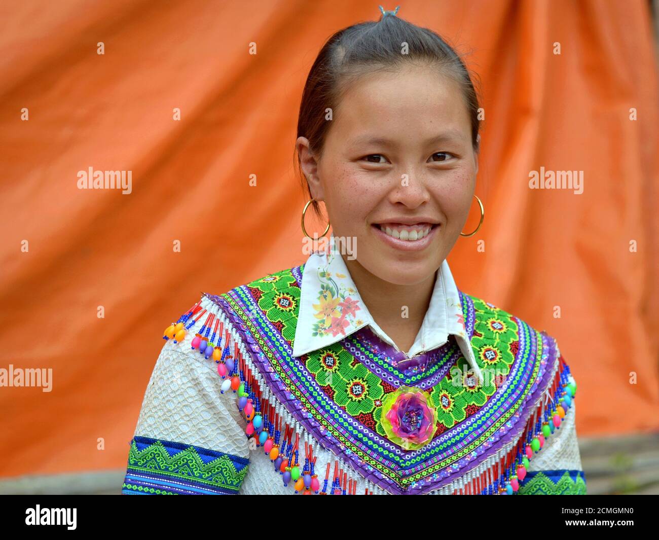 Junge vietnamesische Hmong ethnische Minderheit Hügel-Stamm Frau mit goldenen Reifen Ohrringe trägt bunt bestickte traditionelle Kleidung. Stockfoto