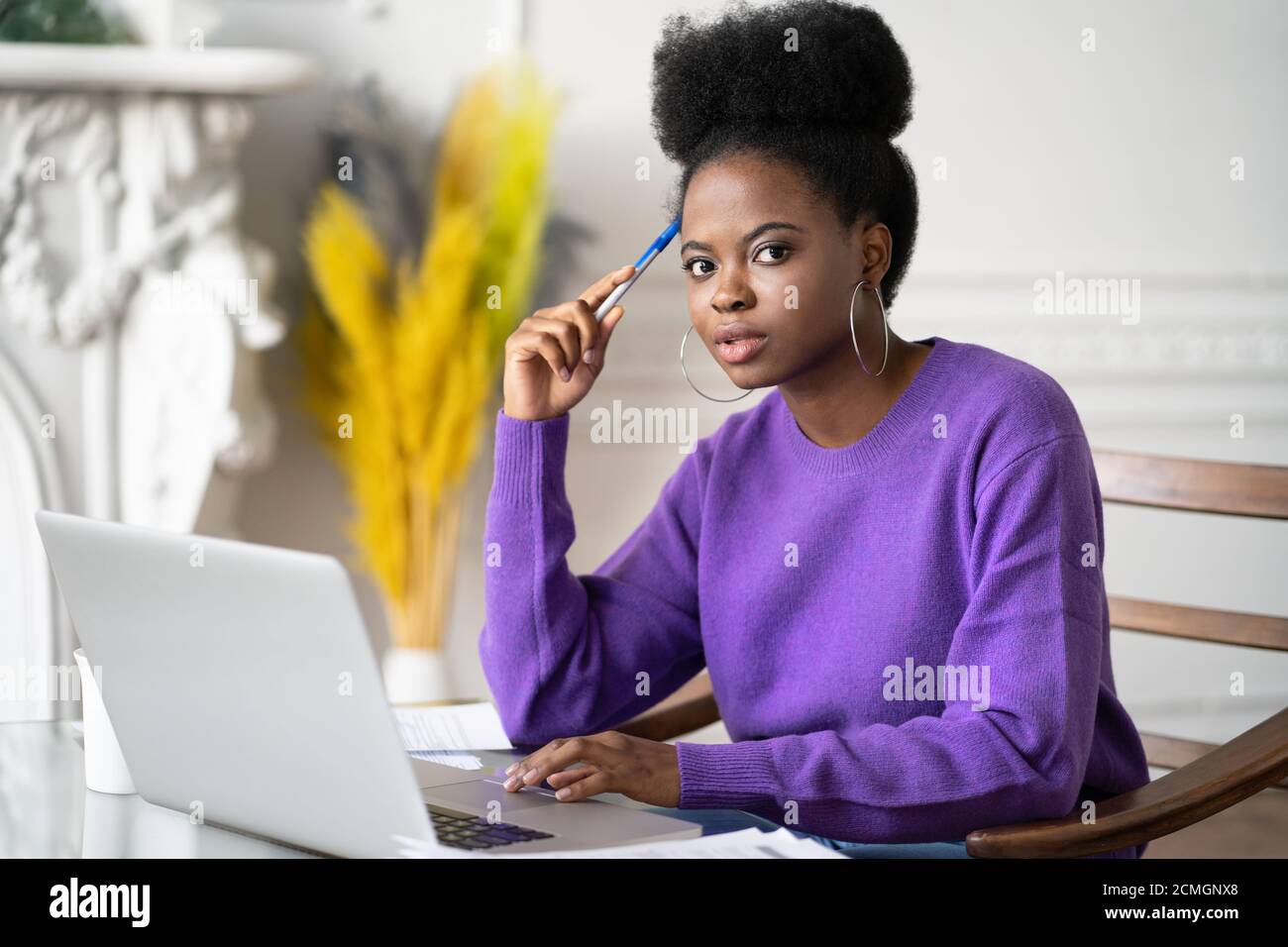 Portrait der afro-amerikanischen Millennial Student Frau mit afro Frisur Blick auf die Kamera, während Recherchen Browsing Informationen auf Laptop, prepa Stockfoto