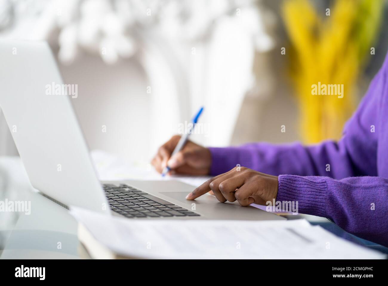 Nahaufnahme einer afroamerikanischen Mitarbeiterin oder Studentin mit Laptop, berührt das Touchpad mit dem Finger, macht Notizen mit dem Stift. Selektiver Weichfokus. Stockfoto