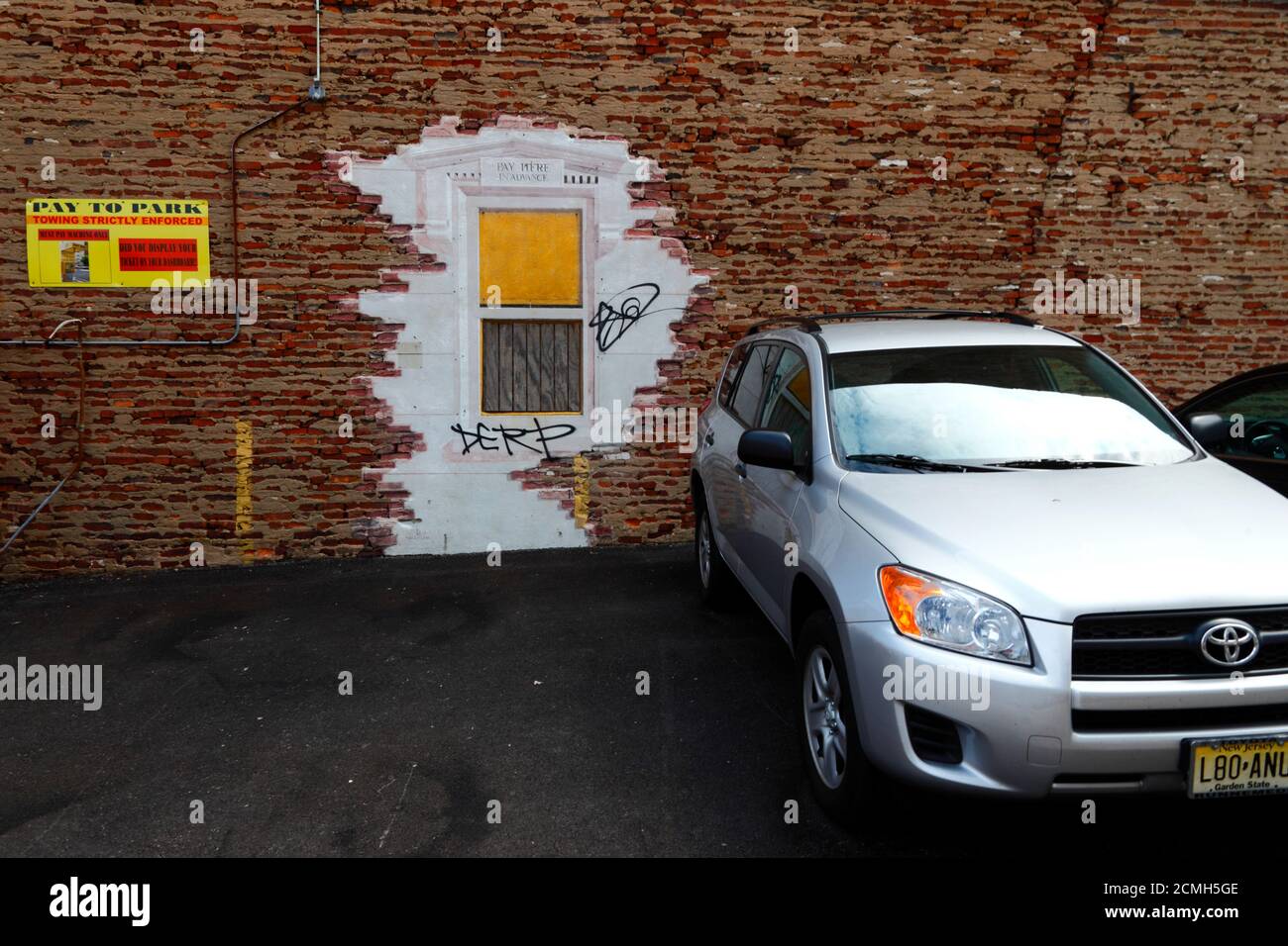 Das Toyota-Auto parkte neben dem Fenster „Pay here in Advance“ in einer Mauer aus alten Backsteinbauten neben dem Parkplatz in Baltimore, Maryland, USA Stockfoto