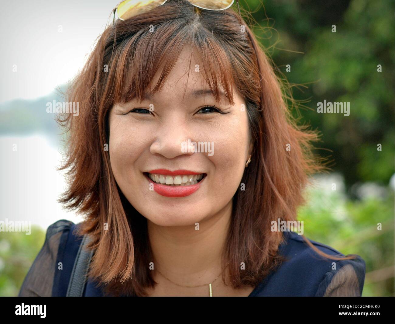 Erfolgreiche vietnamesische Geschäftsfrau lächelt für die Kamera und zeigt ihren schimmernden Zahndiamanten. Stockfoto