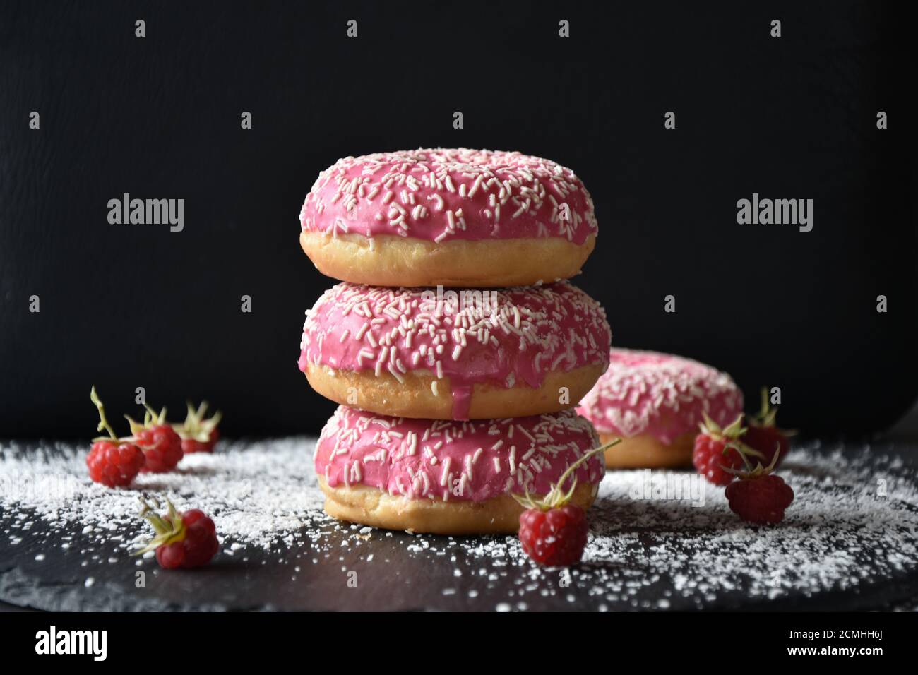 Ein Stapel mit rosa Donuts auf dunklem Hintergrund Stockfoto