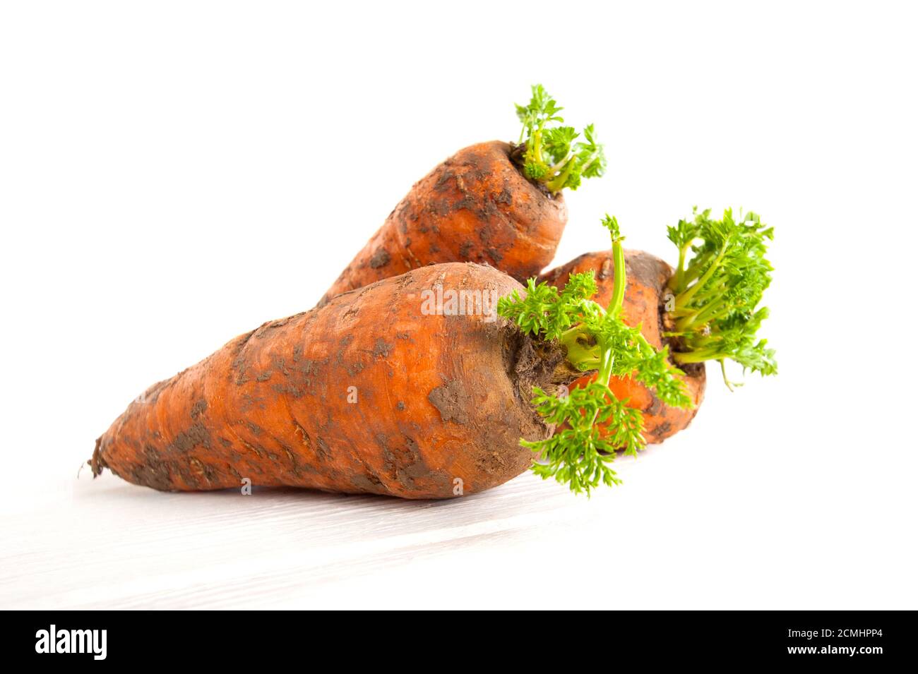 Frische junge Karotten mit Tops auf weißem Hintergrund. Stockfoto