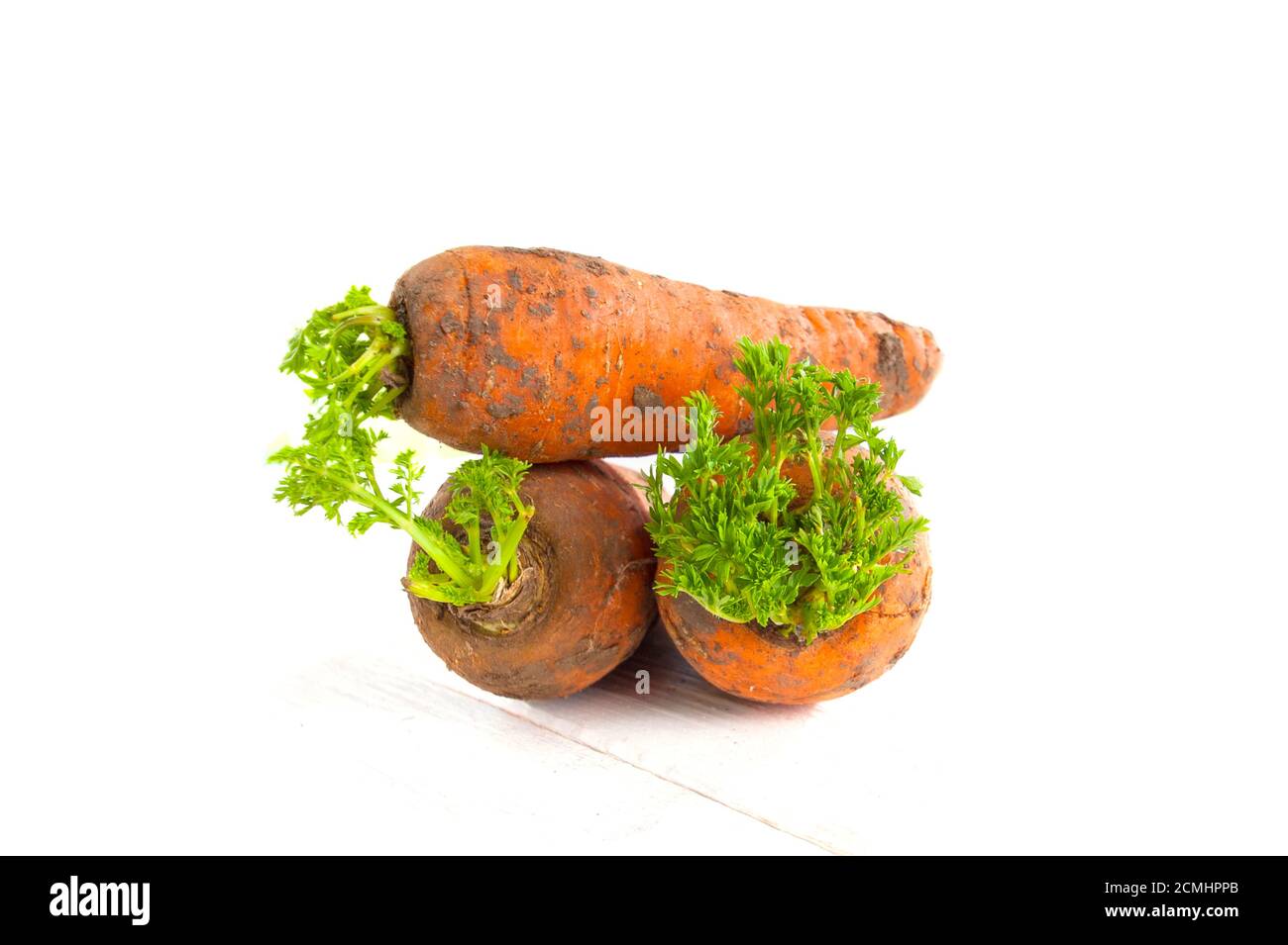 Drei frisch verdaute junge Karotten mit einer Tischplatte auf einem weißen Holztisch. Stockfoto