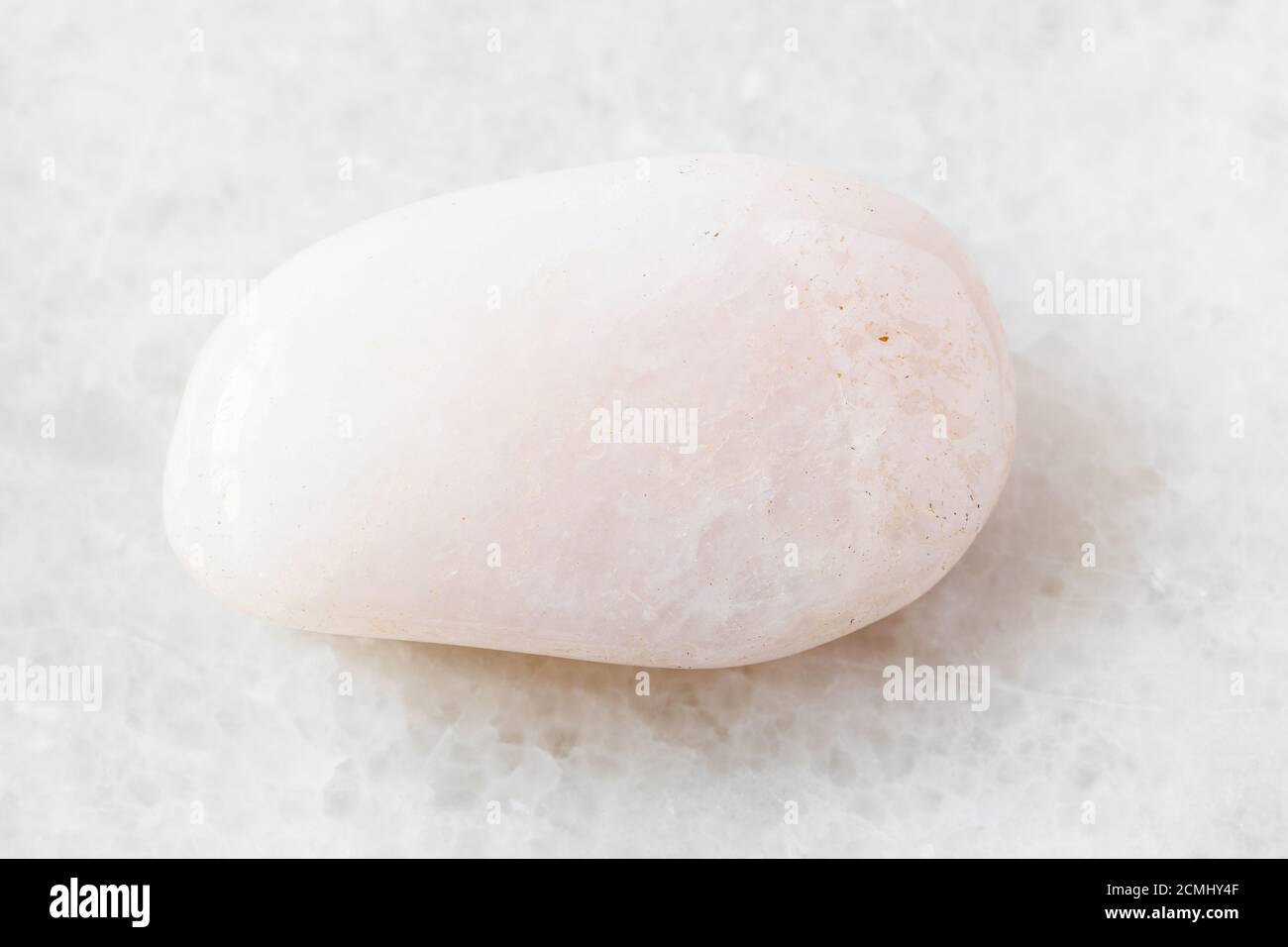 Nahaufnahme der Probe des natürlichen Minerals aus der geologischen Sammlung - Gestromter Petalit-Stein auf weißem Marmor-Hintergrund Stockfoto