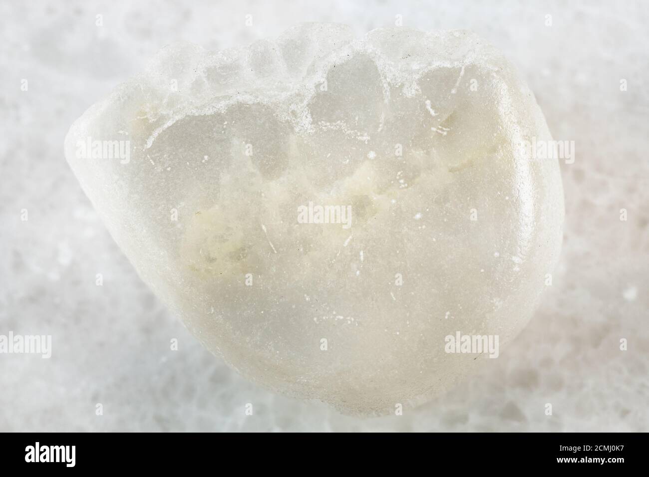 Nahaufnahme der Probe des natürlichen Minerals aus geologischer Sammlung - polierter Ulexit (TV-Stein) Stein auf weißem Marmorgrund aus Kalifornien, USA Stockfoto