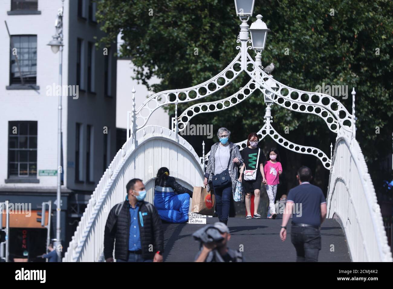 Maskierte Menschen überqueren die Ha'Penny Bridge im Stadtzentrum von Dublin und rufen die Gesundheitsbehörden dazu auf, weitere Details zu den Ausbrüchen von Covid-19 in Unternehmen und öffentlichen Einrichtungen zu veröffentlichen. Stockfoto