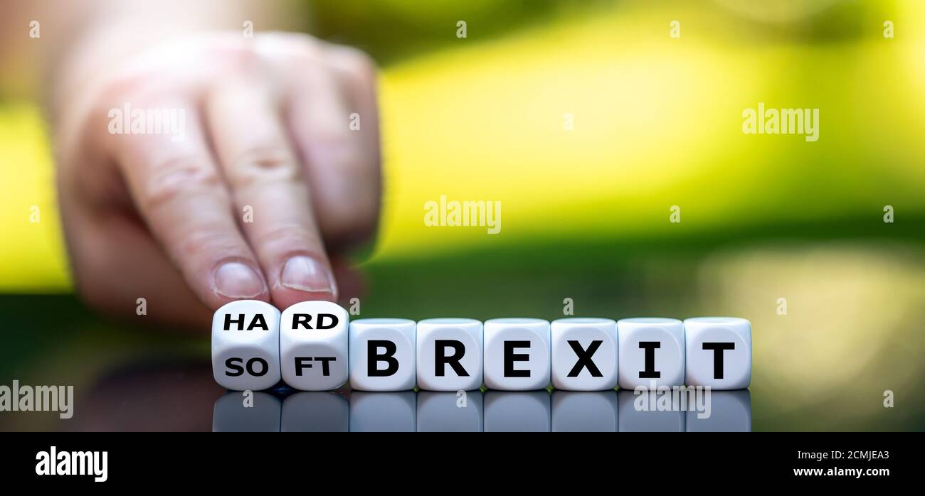 Hand dreht Würfel und ändert den Ausdruck "weicher brexit" in "harter brexit". Stockfoto