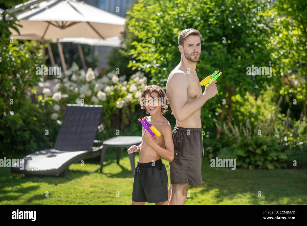 Papa und Sohn mit Wasserpistolen machen sich bereit zu spielen Stockfoto