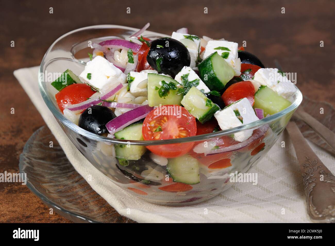 griechischer Salat Orzo Nudeln mit schwarzen Oliven, roten Zwiebeln und Gurken, Tomaten, Feta und Kräutern Stockfoto