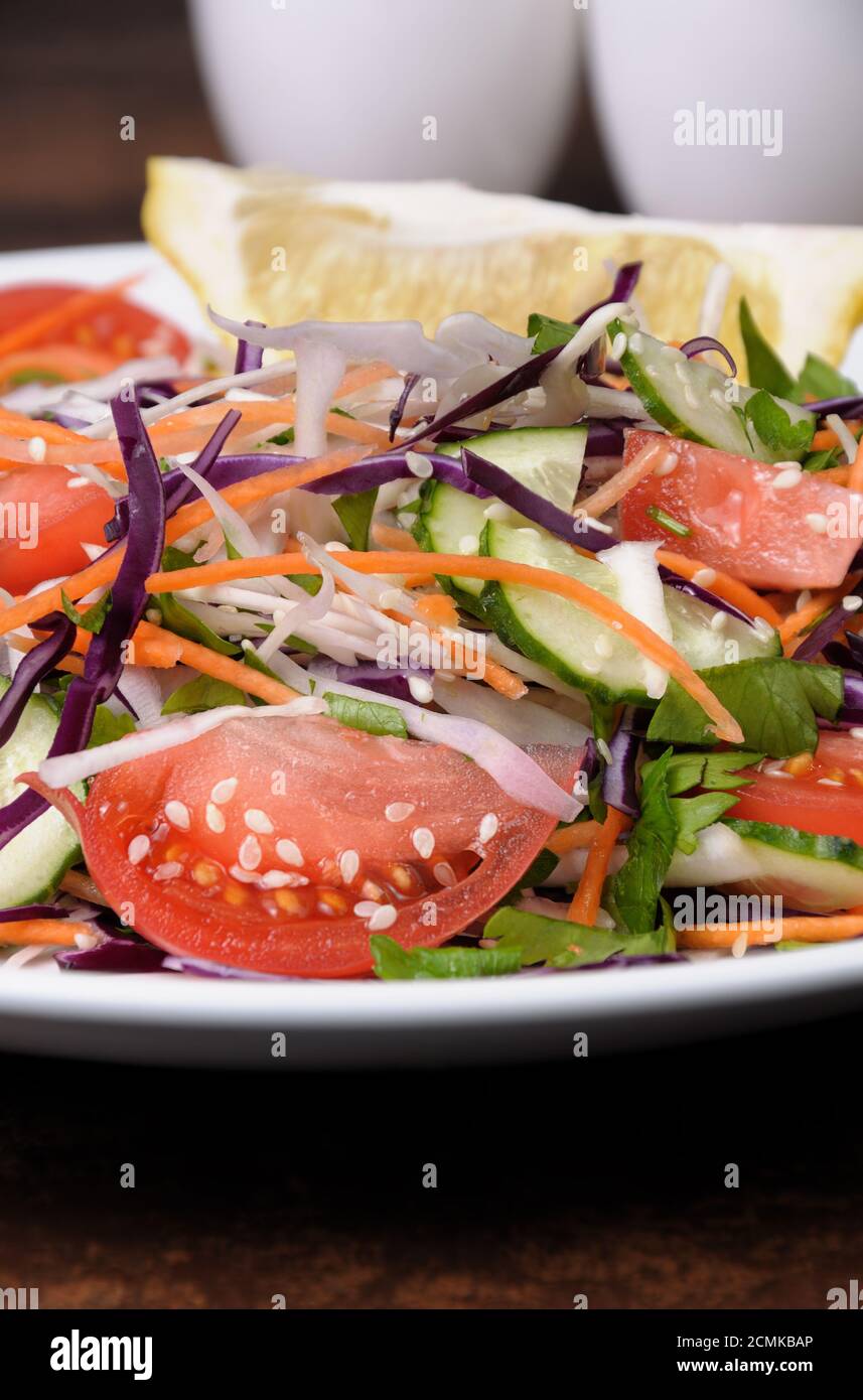 Salat aus weißen und blauen gehackten Kohl, Karotten, Gurken, Tomaten gekleidet mit Öl, Zitrone, Sesam Stockfoto