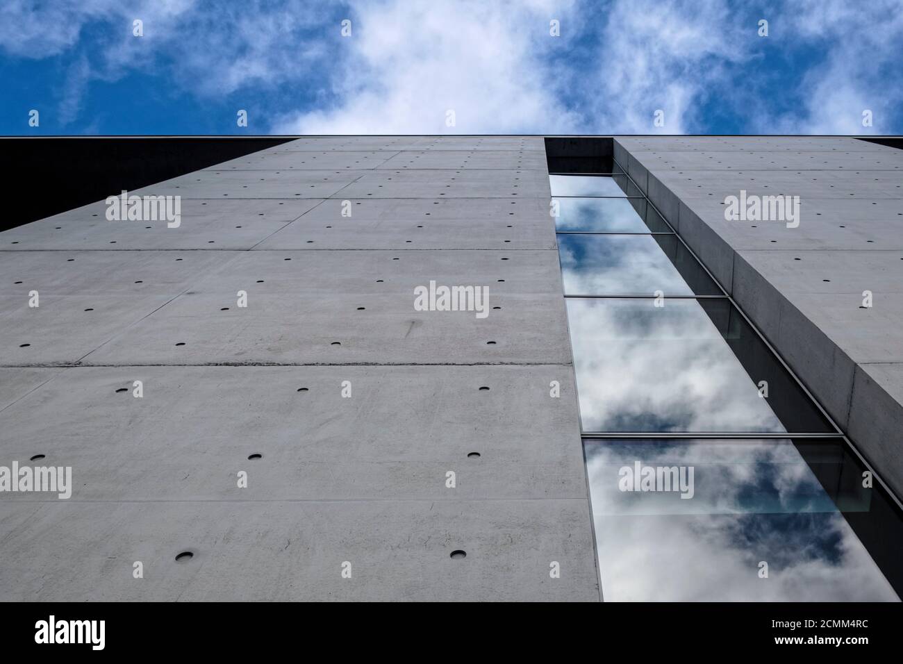 Modernes Gebäude vor blauem bewölktem Himmel. Ansicht von unten nach oben. Glasspiegelung und Betonfassade, Berlin Stockfoto