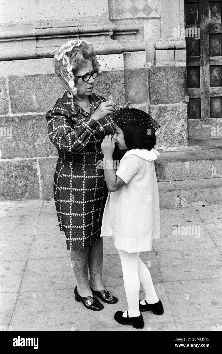 Mazatlan Mexiko 70er Jahre. Mutter und Tochter vor der römisch-katholischen Kirche machen sich bereit. Mutter fixiert ihre Töchter Kopf Abdeckung Mantilla, bevor sie in die Kirche gehen. 1973 HOMER SYKES Stockfoto