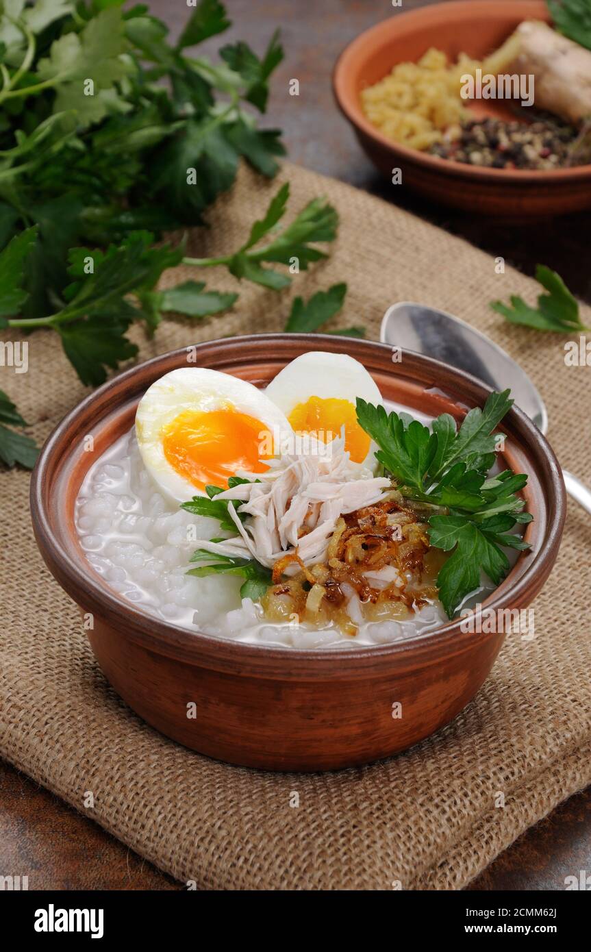 Reis Brei Ingwer Congee mit Ei, Huhn, knusprigen Schalotten und Petersilie Stockfoto