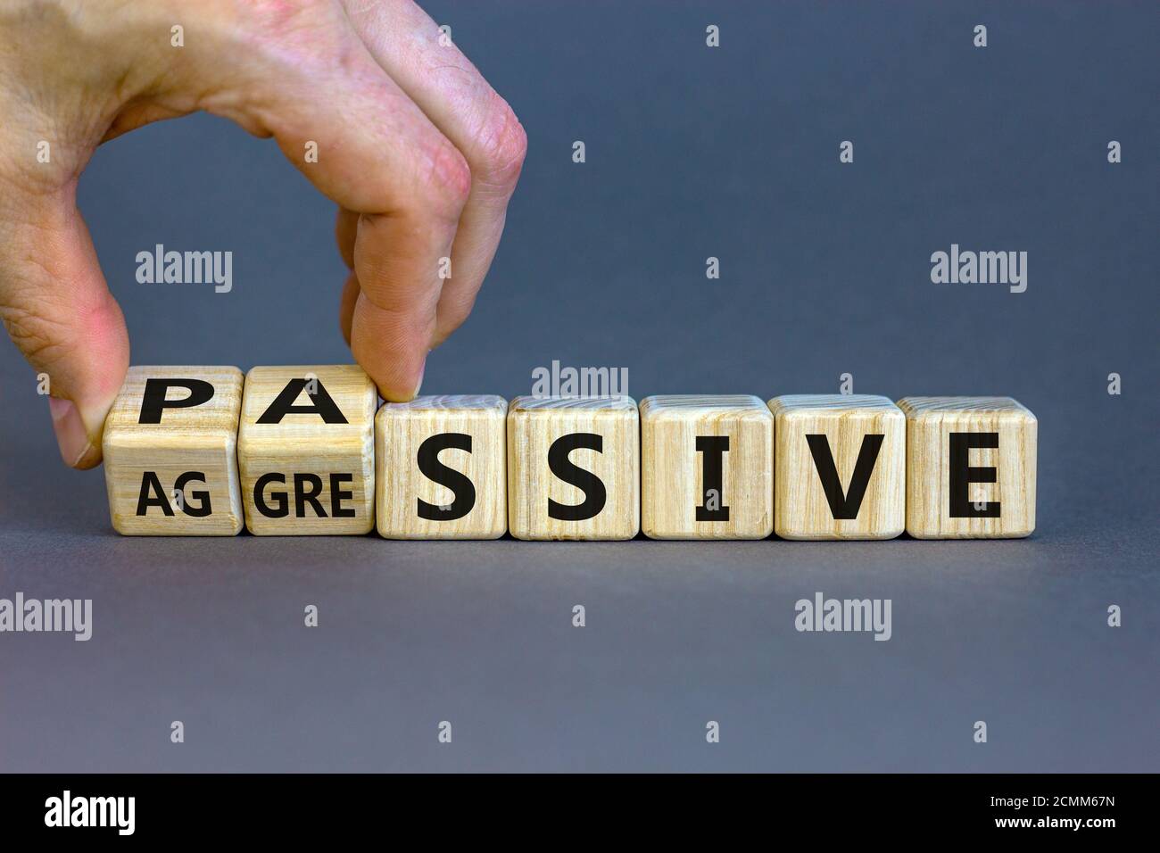 Hand dreht Würfel und ändert das Wort "passiv" zu "aggressiv", oder umgekehrt. Business und psychologisches Konzept. Schöner grauer Hintergrund, Kopie sp Stockfoto
