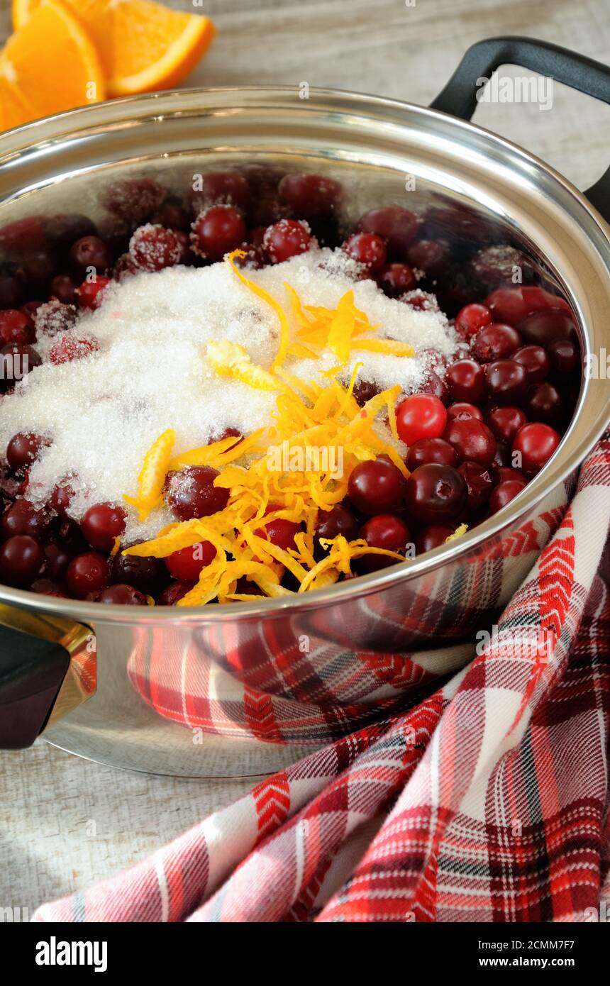 Frische Cranberries mit Zucker und Zitronenschale in einem Topf abgedeckt Stockfoto