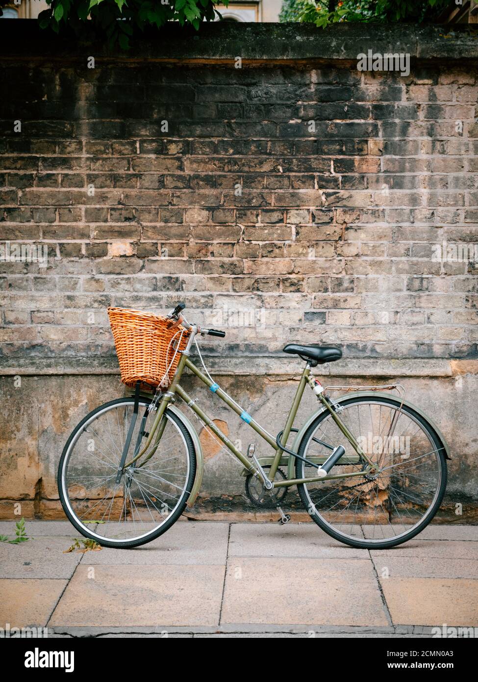 Ein Traditionsfahrrad, das sich gegen eine College-Wand lehnt Cambridge, Großbritannien Stockfoto