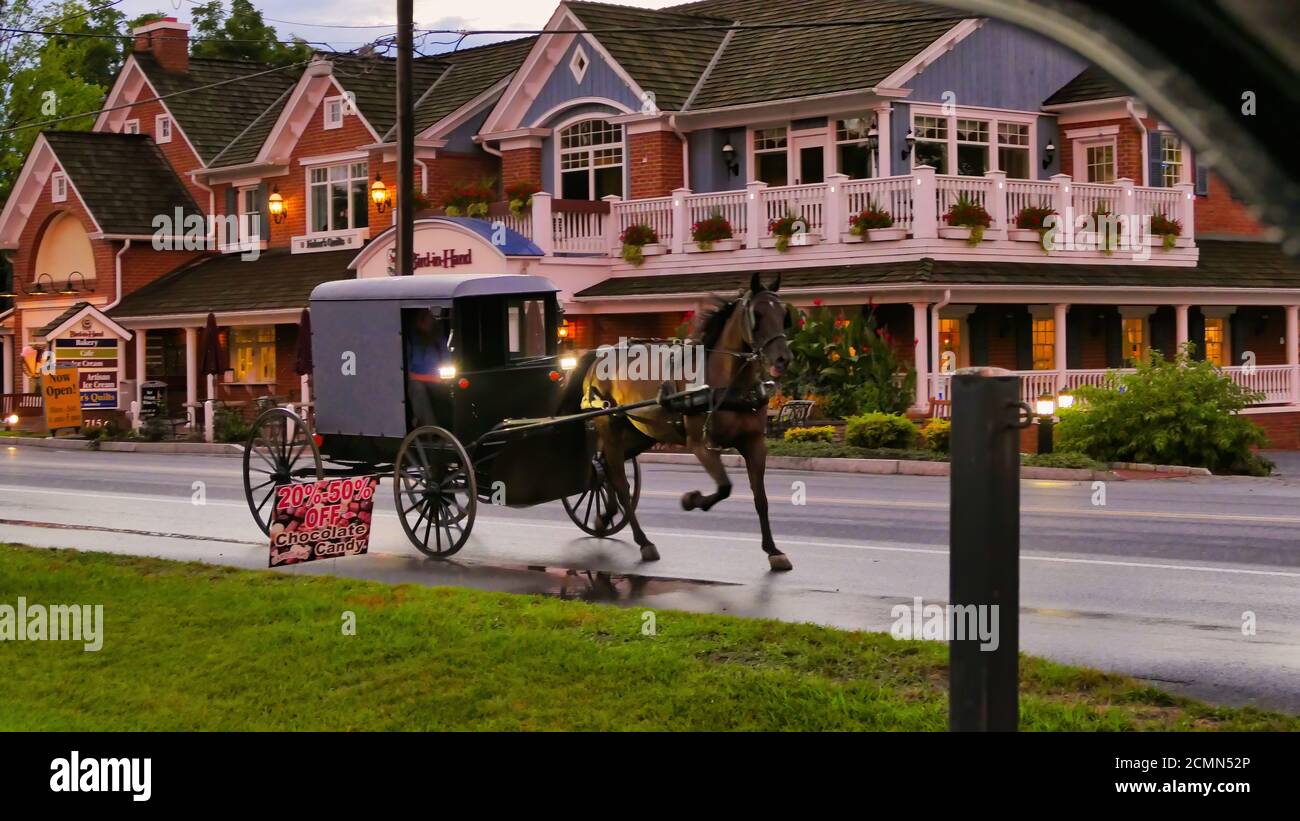 Amish Horse and Buggy Passing Stores auf einer Landstraße. Hochwertige Fotos. An einem späten Nachmittag Stockfoto