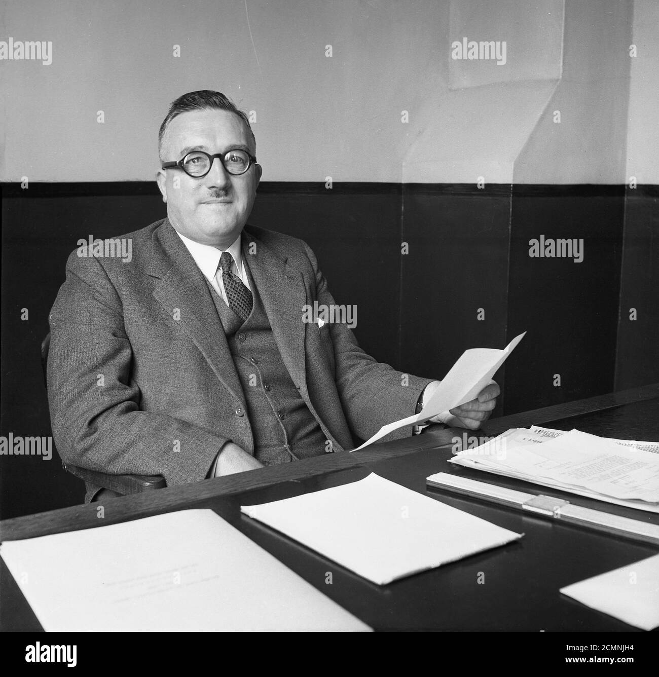 1950er Jahre, historisches Porträt eines leitenden Geschäftsleiters der British Ever Ready Battery & Electrical Company, eines der führenden britischen Produktionsunternehmen dieser Zeit, an seinem Schreibtisch in seinem spartanischen Büro in England, Großbritannien, sitzend. Stockfoto