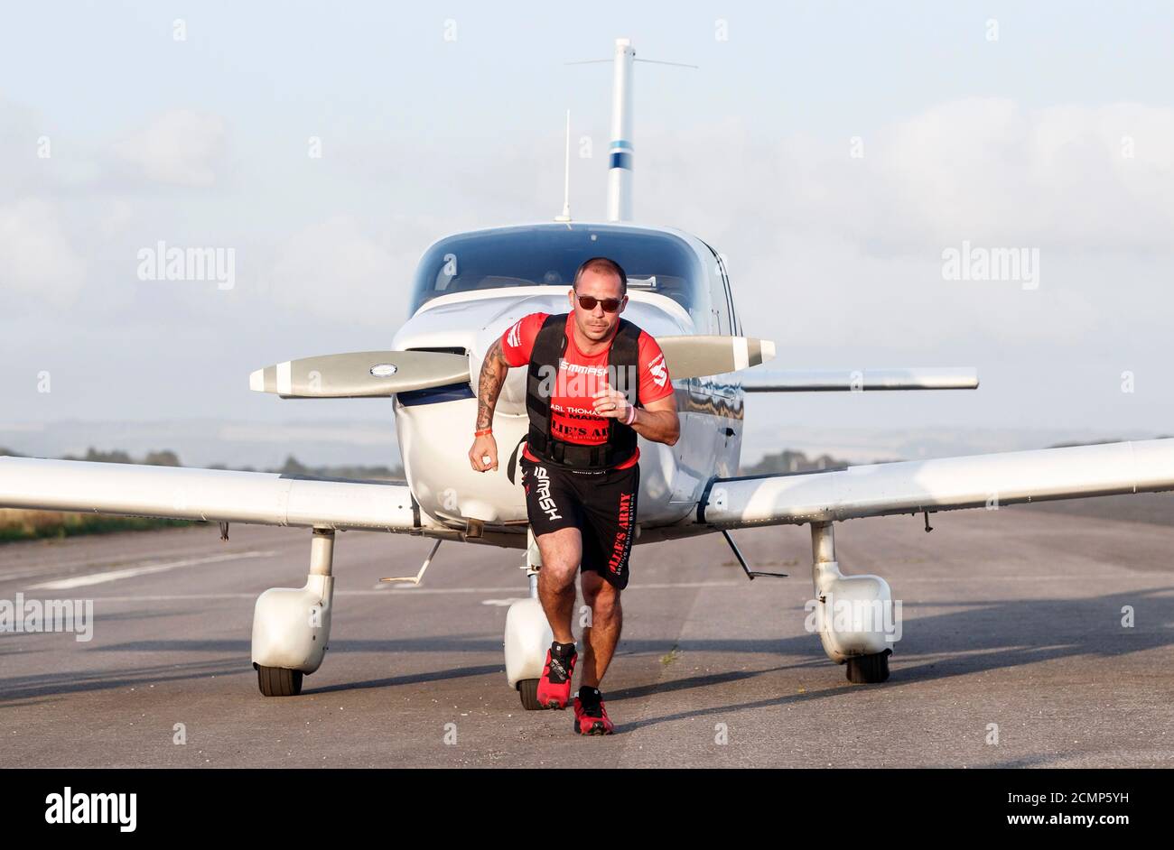 Der Kickboxen-Weltmeister Carl Thomas überquert die Ziellinie, um einen Marathon zu absolvieren, während er am Elvington Airfield bei York ein Flugzeug zieht. Stockfoto