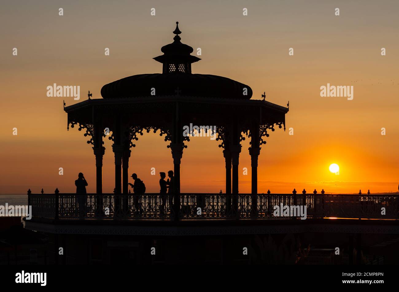 Ein Paar tanzt bei Sonnenuntergang im viktorianischen Bandstand, bekannt als Birdcage, an der Kings Road, Brighton Seafront. Ungeschliffen Stockfoto