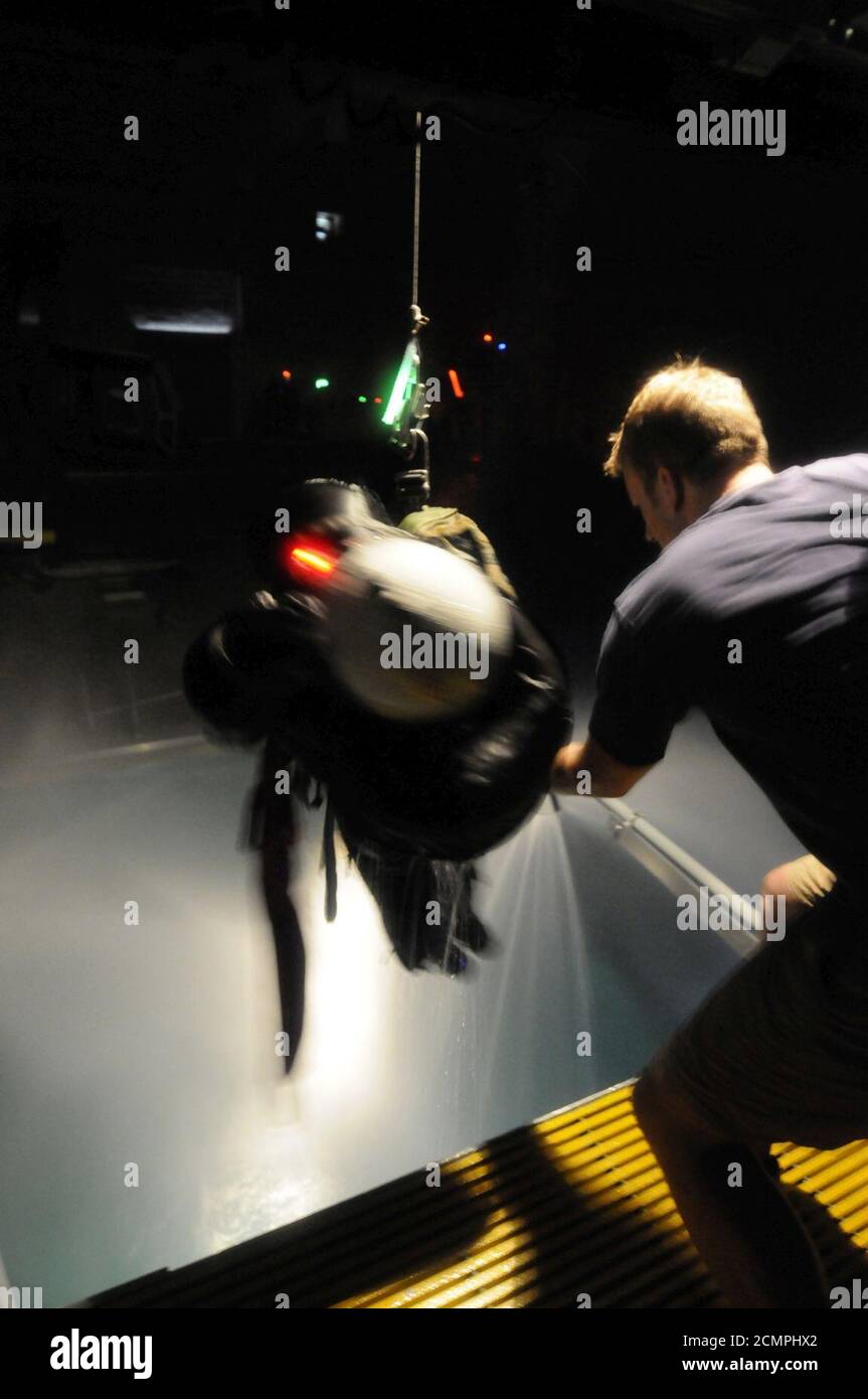 Navy Diver 1. Klasse ein Instruktor am Aviation Survival Training Kurs, wirft einen Schüler auf einem Hebezeug Stockfoto