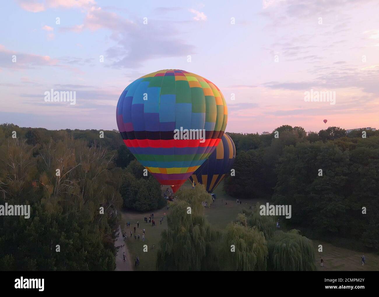 Luftdrohne Ansicht der bunten Heißluftballon fliegen über grünen Park in kleinen europäischen Stadt bei Sommersonnenaufgang, Kiew Region, Ukraine Stockfoto