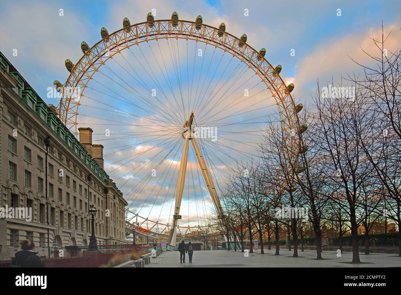 Das London Eye auf der South Bank wurde am frühen Morgen mit zwei Personen zu Fuß aufgenommen. Es ist eine beliebte Touristenattraktion und bietet einen Panoramablick. Stockfoto