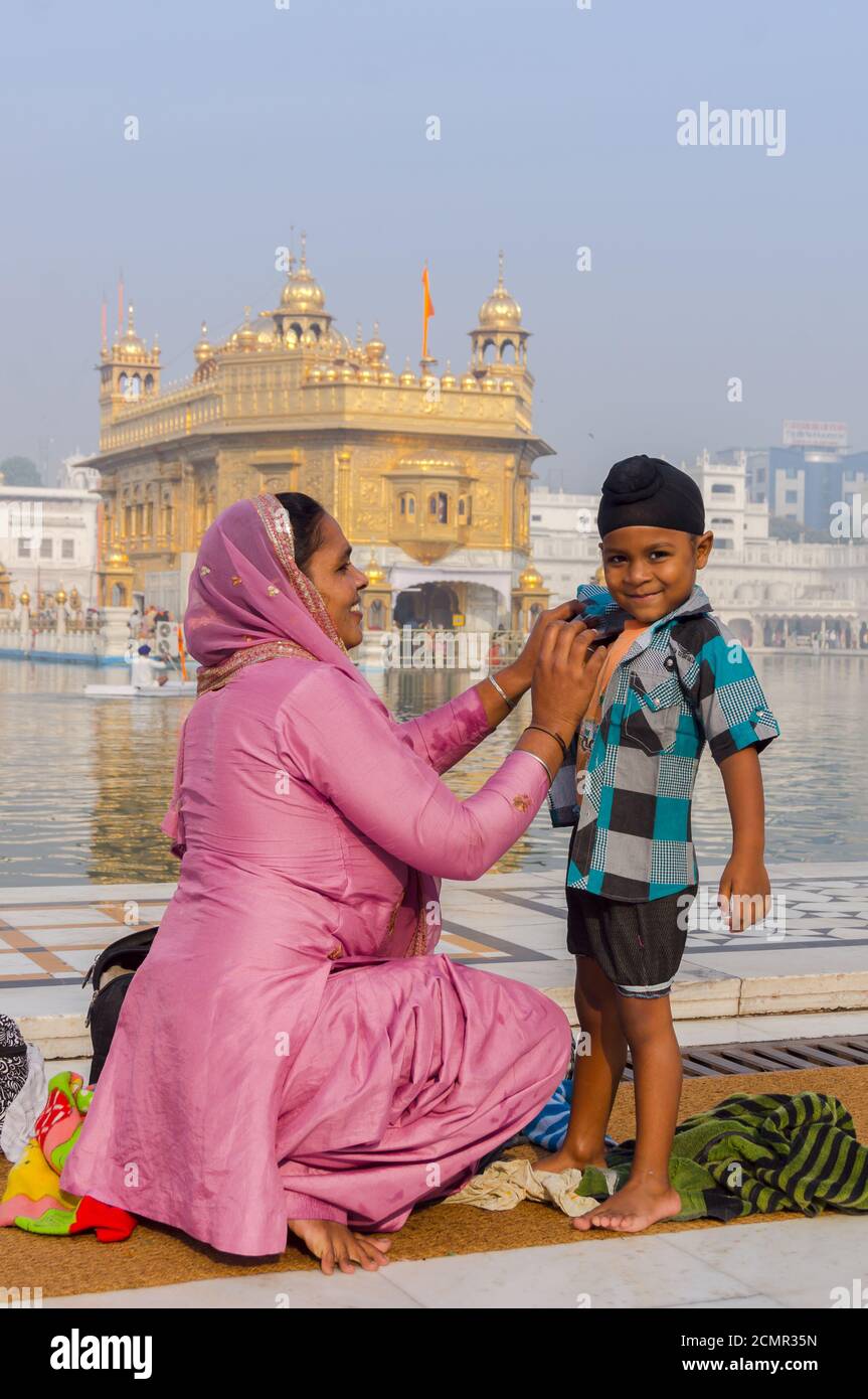 Amritsar, Indien - 21. November 2011: Die Sikh-Familie von Pilgern, Mutter und Sohn, kleidet sich ein Badeplatz im See in der Golden Temple Complex. Stockfoto