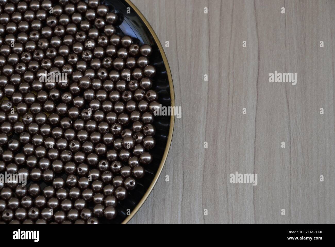 Teller, Teller in schwarzer Farbe mit Perlen oder runder Silberschmuck, auf Holzhintergrund mit Kopierraum, Foto-Zoom Stockfoto