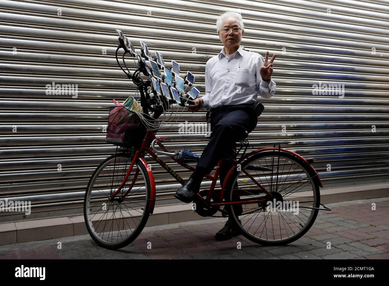 Taiwanese Chen San-Yuan, 70, bekannt als "Pokemon Opa", posiert mit seinem  Fahrrad, während er das mobile Spiel "Pokemon Go" von Nintendo spielt, in  der Nähe seines Hauses mit 15 Handys, in New