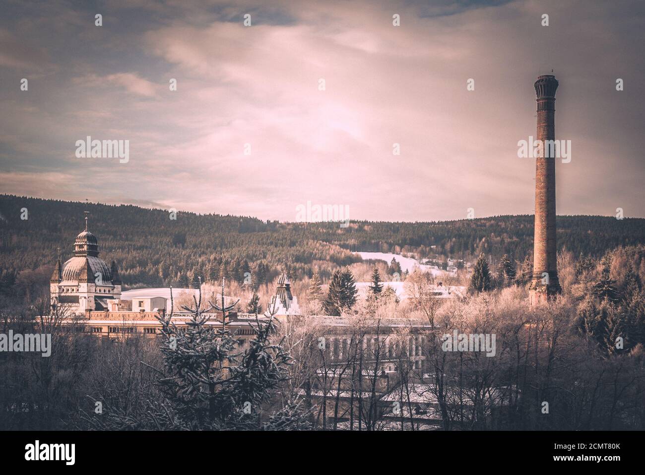 Alte Bergfabrik mit Zierkuppel und hohem Schornstein in Winterlandschaft. Bild im Vintage-Stil. Stockfoto