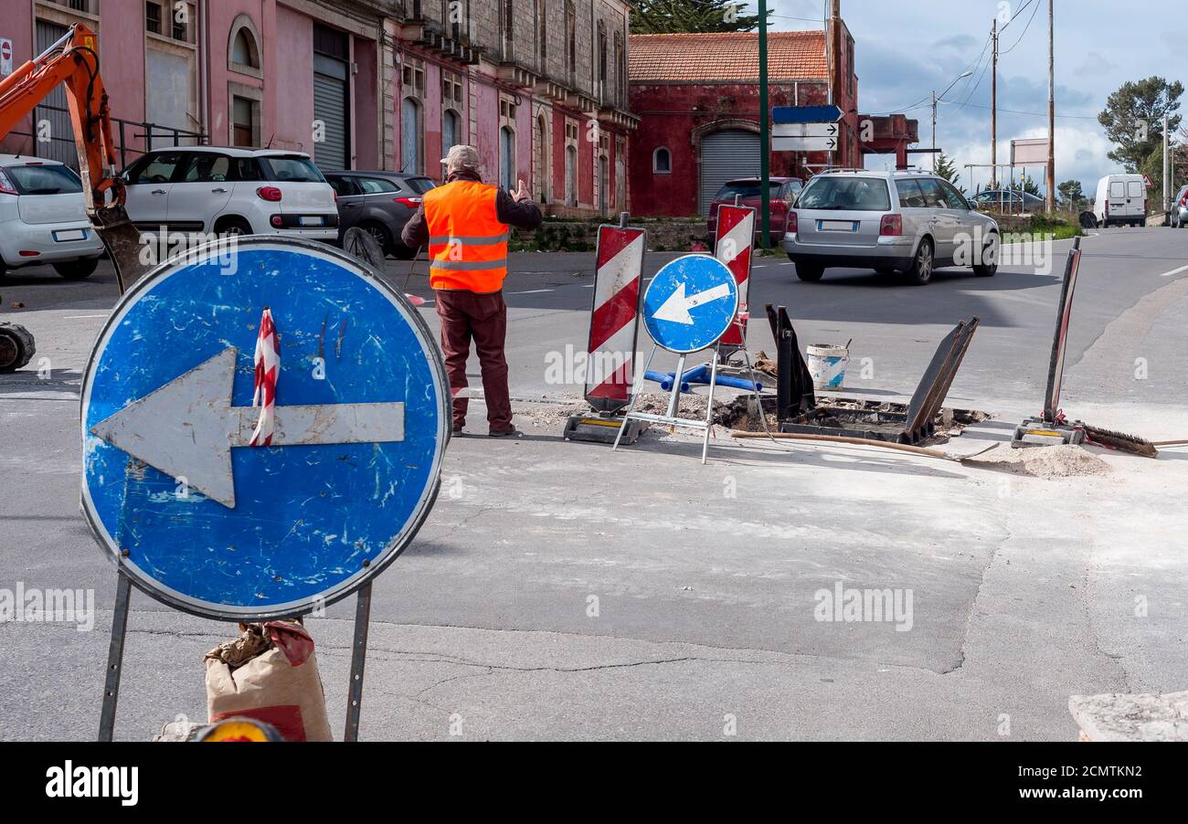 Arbeiter-Movemen regelt den Verkehr von Fahrzeugen in einer Kreuzung Betroffen von Bauarbeiten an der Glasfaserleitung Stockfoto