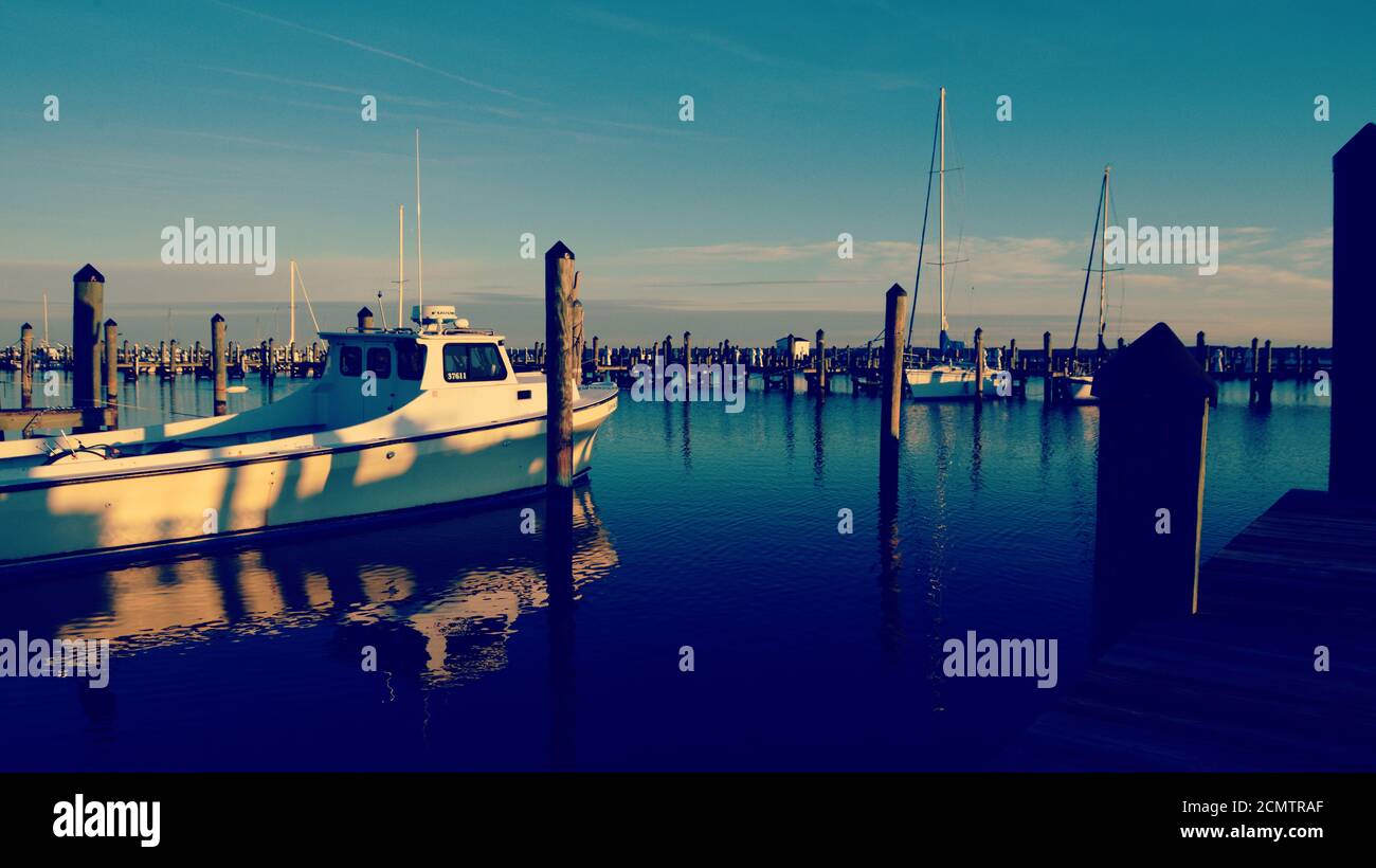Am frühen Morgen Licht auf kleinen Hafen in Cambridge Maryland, mit Reflexionen der Gleichaltrigen und Boote im Wasser. Stockfoto
