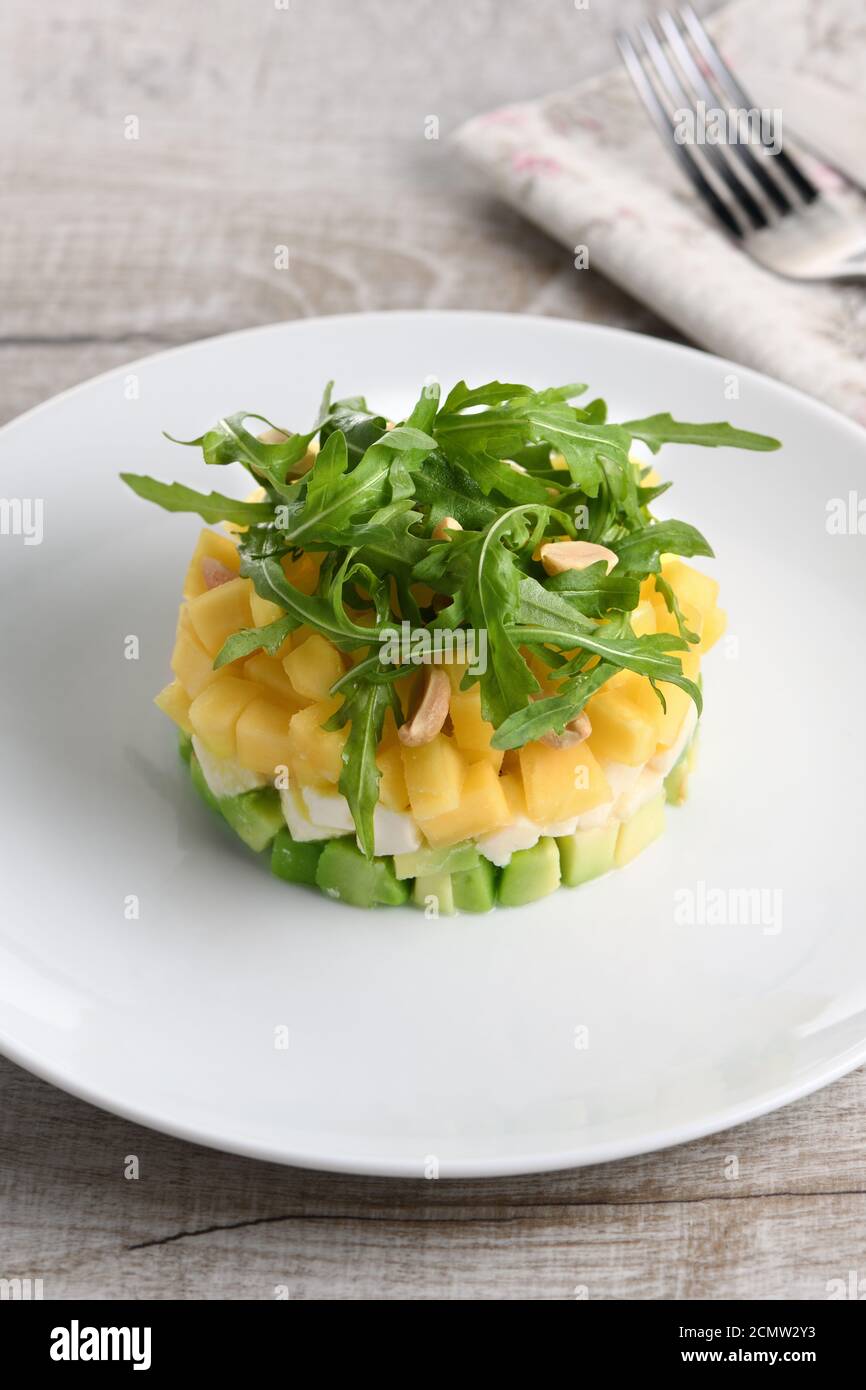 Frische Avocado, Mango, Mozzarella, und Rucola Salat, gewürzt mit Muttern Stockfoto