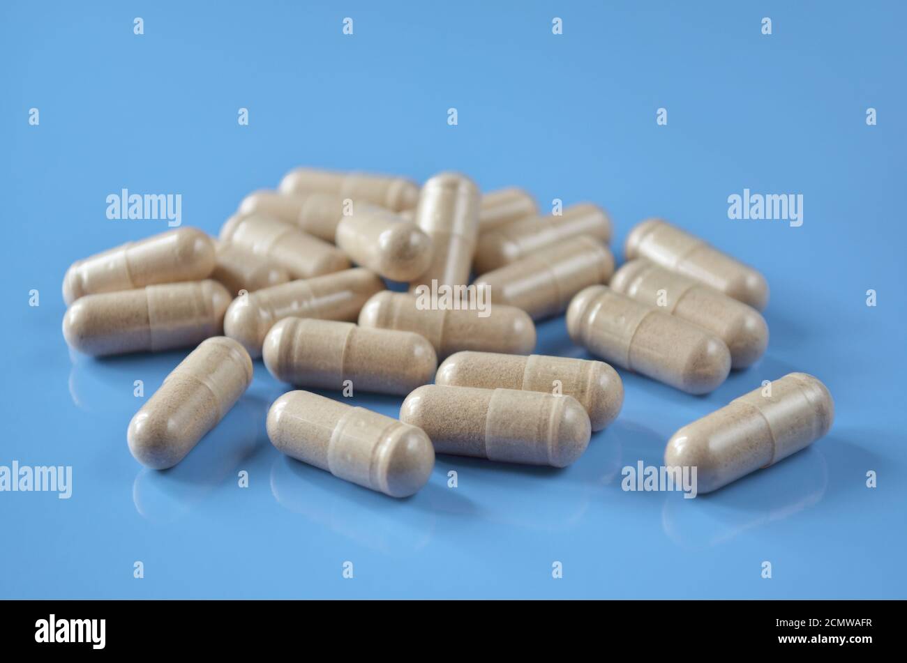 Heap Pillen-Kapseln auf einem hellblauen Hintergrund, Nahaufnahme. Geringe Schärfentiefe, selektiver Fokus. Gesundheitskonzept. Stockfoto