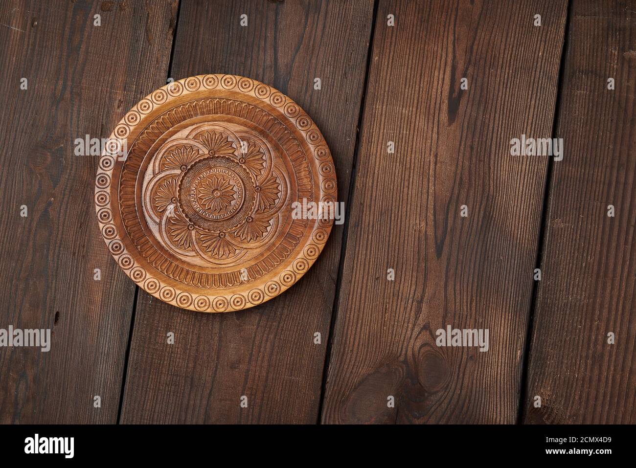 Leere runde braun geschnitzte dekorative Platte auf einem Holz stehen Hintergrund Stockfoto