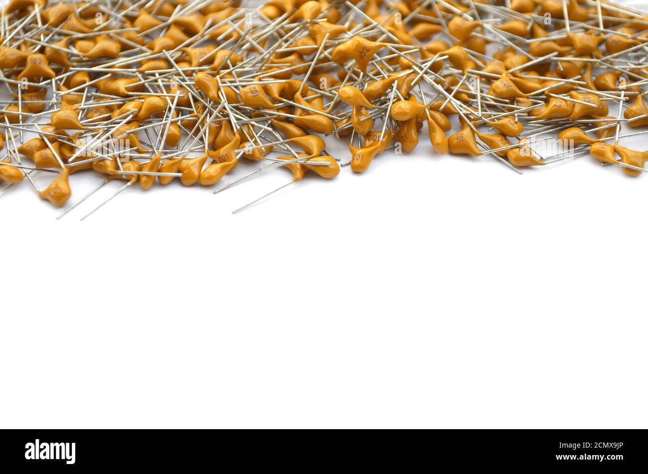 Viele gelbe Kondensatoren befinden sich oben mit Kopierplatz. Elektronische Bauteile isoliert auf weißem Hintergrund, selektiver Fokus. Stockfoto