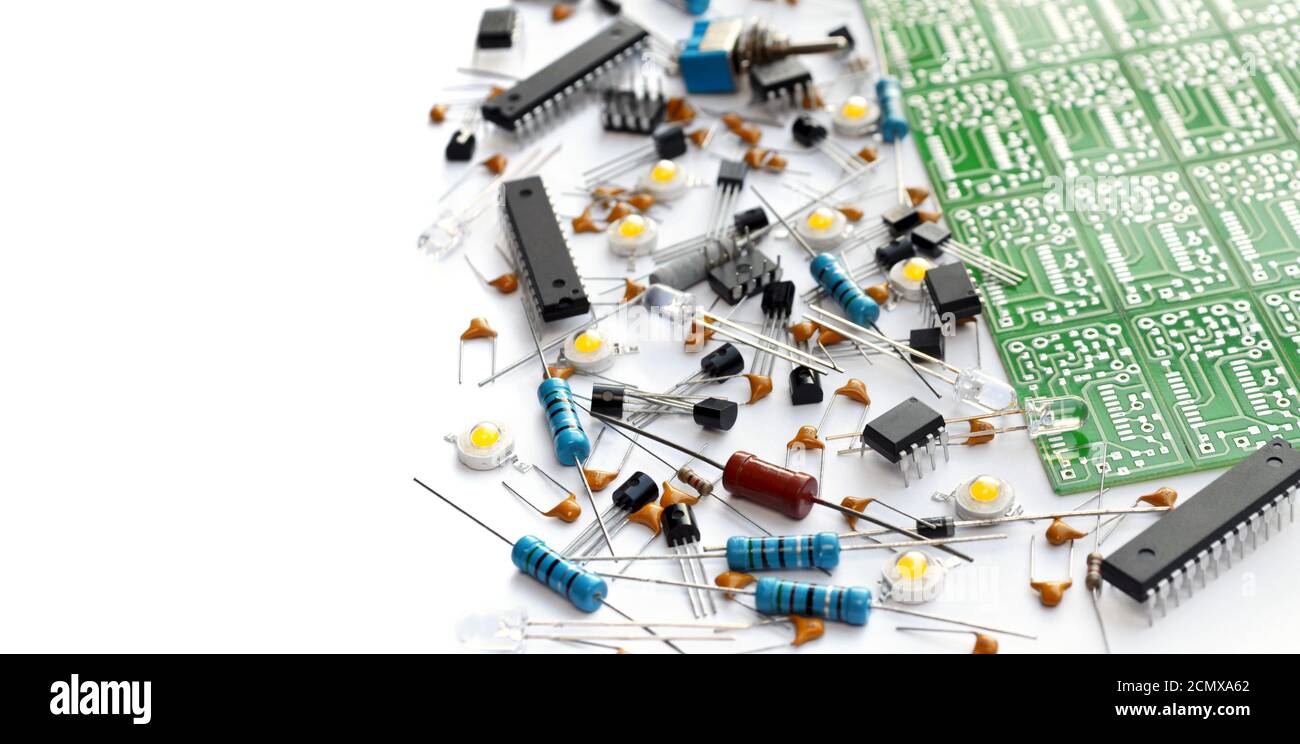 Verschiedene elektronische Komponenten in der Nähe von grünen elektronischen Leiterplatte auf weißem Hintergrund mit Kopierraum angeordnet. Nahaufnahme, selektiver Fokus Stockfoto