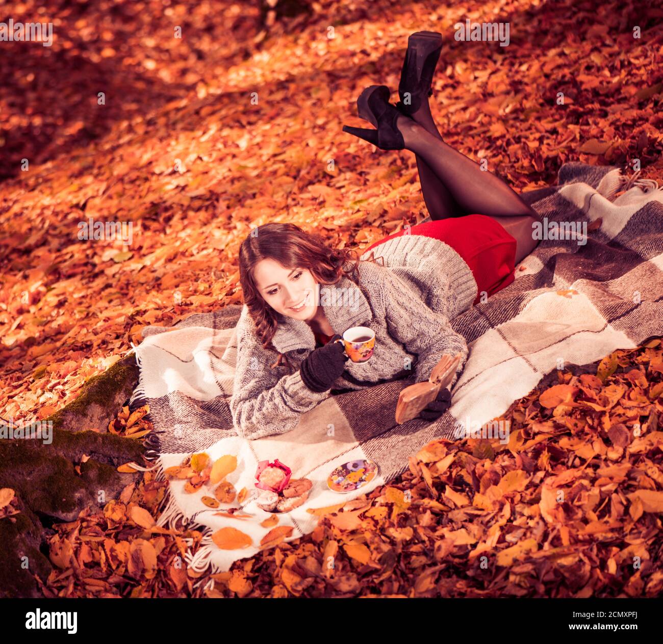 Junge positive Brunet Frau Porträt mit Cookie und Buch an Herbstwald Stockfoto