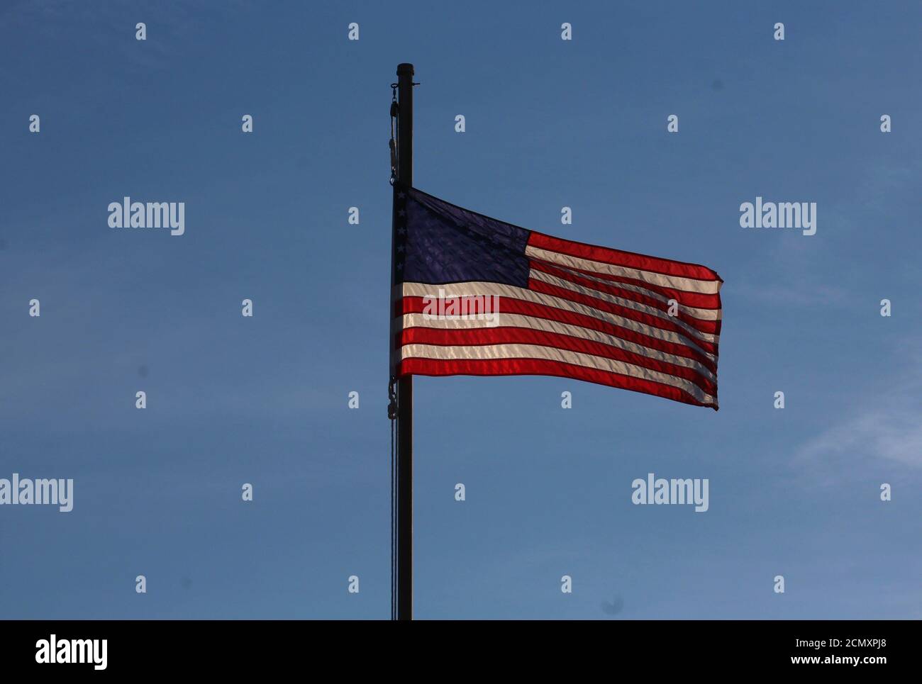 Eine amerikanische Flagge flattert in der Brise am Kure Beach Pier vor dem Hintergrund eines Carolina Blue Sky. Stockfoto