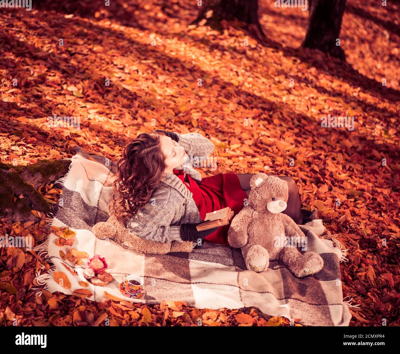 Junge positive Brunet Frau Porträt mit Cookie und Buch an Herbstwald Stockfoto